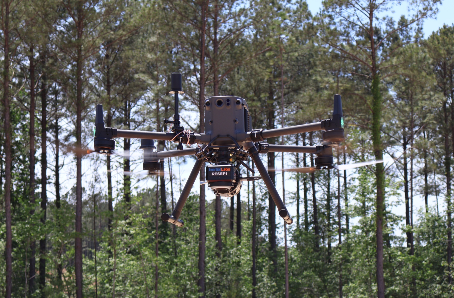 Drone with LiDAR payload flying over wooded terrain